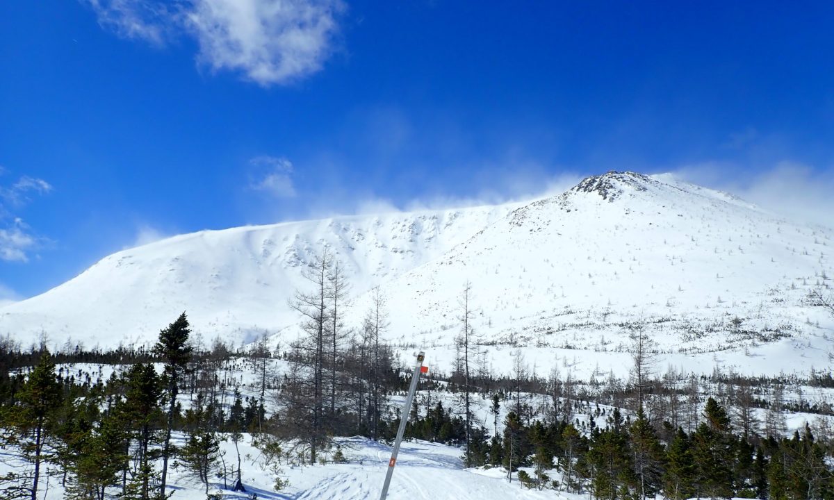 Le vent se lève-t-il ? Surveillez de près le transport de neige par le vent, qui peut alourdir les pentes sous le vent (celles situées du côté opposé à la direction du vent). Les nuages clairs visibles au sommet sur cette photo sont en réalité des panaches de neige poussés par le vent au-dessus de la crête. La pente sur laquelle cette neige se dépose sera alourdie et plus susceptible de déclencher une avalanche.